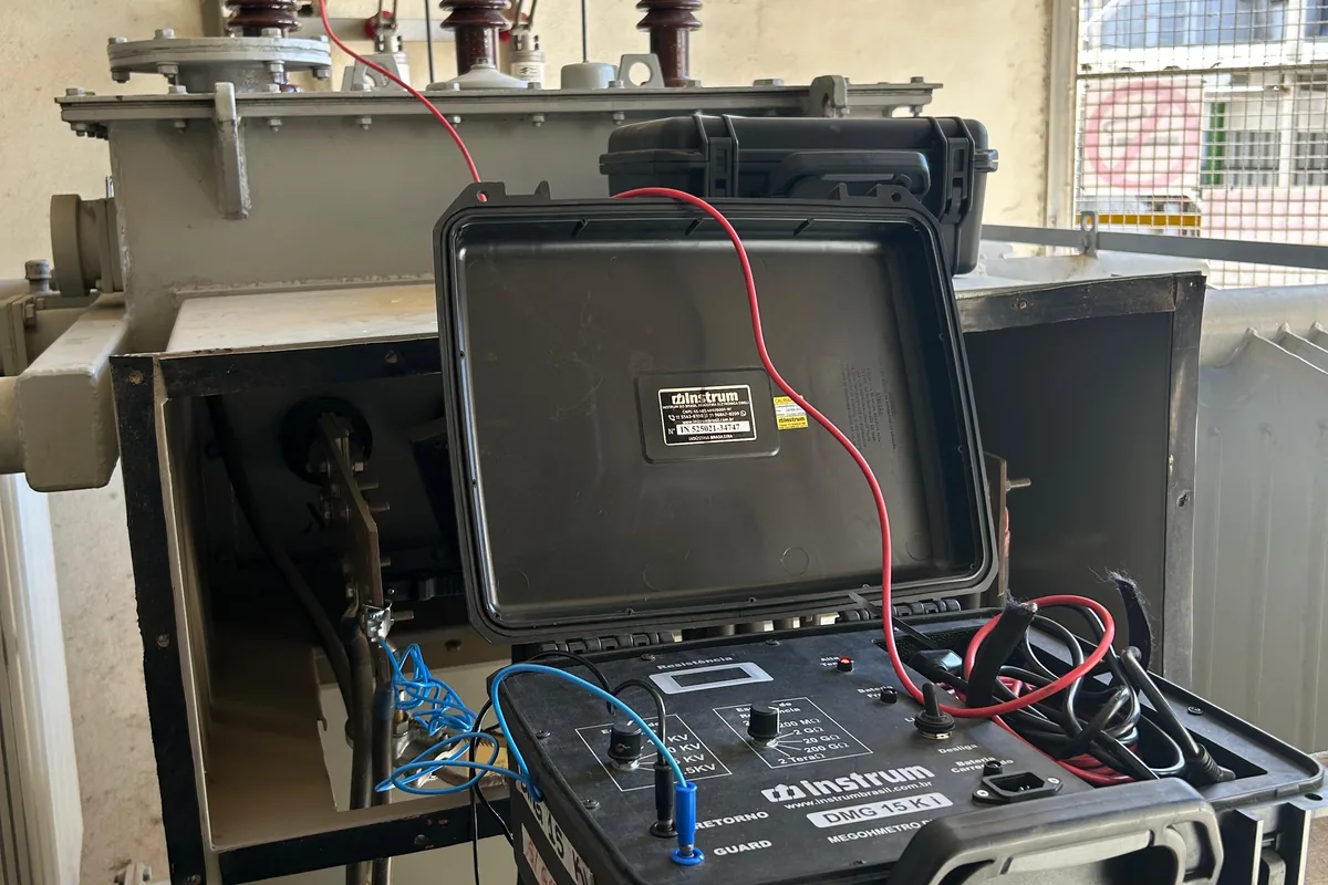 Instrumento de ensaio conectado a um transformador, dentro da subestação.